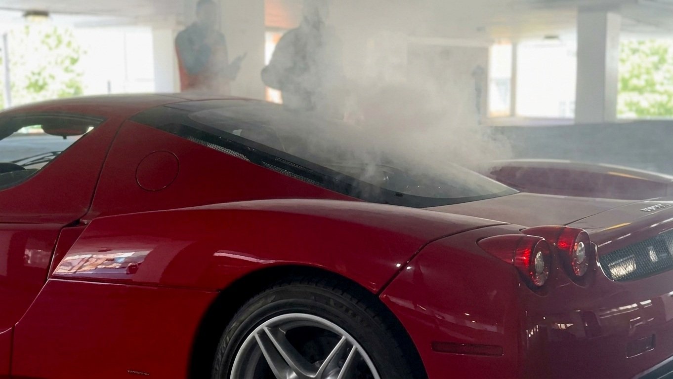Ferrari Enzo starts smoking while driving in a parking, onlookers shout warnings